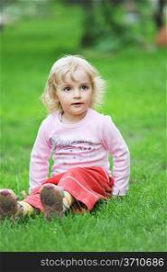 little girl sitting on green grass