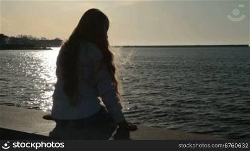Little girl sitting on the embankment at sunset Sevastopol