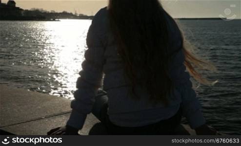 Little girl sitting on the embankment at sunset Sevastopol