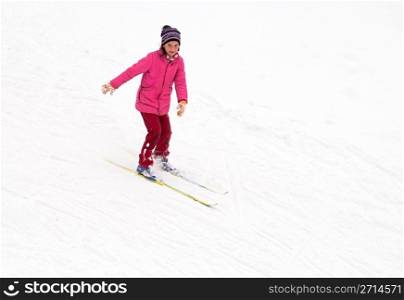 Little girl skiing fast down the hill in snow winter day