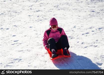 Little girl sledding at Sierra Nevada ski resort wearing snow clothes.. Little girl sledding at Sierra Nevada ski resort.