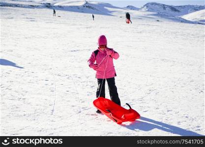 Little girl sledding at Sierra Nevada ski resort wearing snow clothes.. Little girl sledding at Sierra Nevada ski resort.