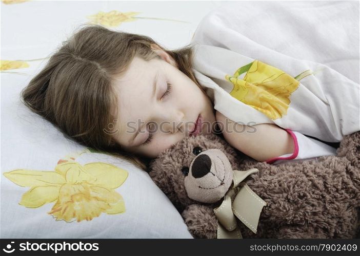 Little girl sleeping in her bed with teddy bear