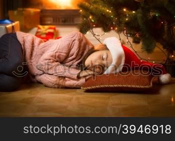 Little girl sleeping on floor at fireplace under Christmas tree
