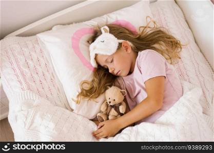 Little girl sleeping with a soft toy in her bed on a pillow is a sweet calm sleep of a child.