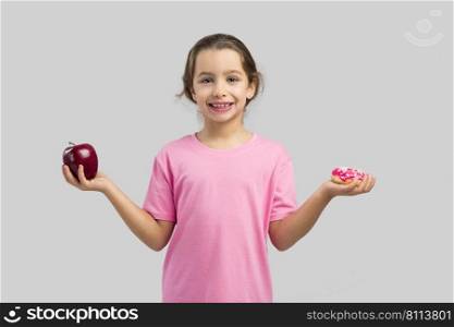 Little girl smiling and choosing between a apple and a donut
