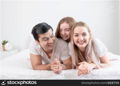 little girl smiling with mother and father on bed together in bedroom at home, young happy family concept
