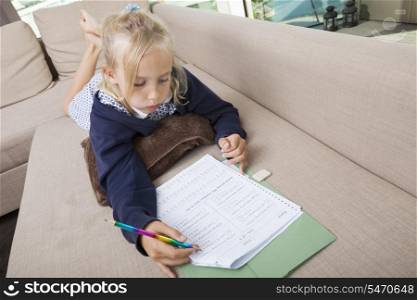 Little girl solving mathematics sums on sofa