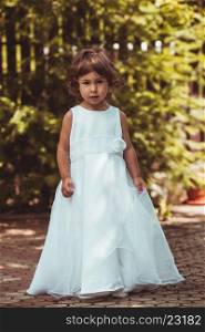 Little girl spinning around in ornate dress outdoor. Girl in dress
