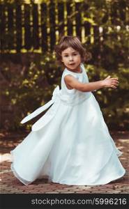 Little girl spinning around in ornate dress outdoor. Girl in dress