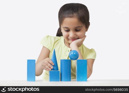 Little girl stacking geometry shaped blocks isolated over white background