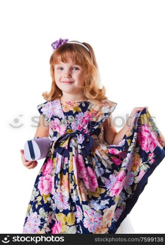 little girl stands with clutch, smiles and holing in hand her dress with flowers on white background