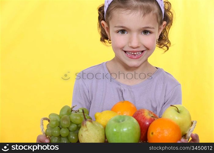 Little girl stood with fruit arrangement