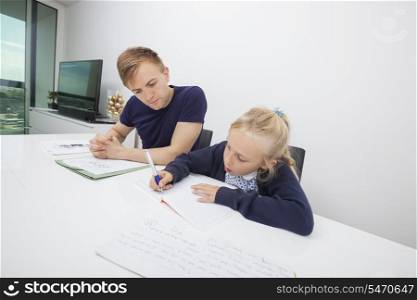 Little girl studying while sitting by father at table