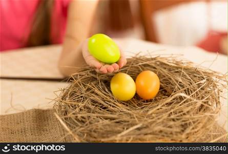 Little girl taking Easter egg from the nest