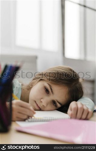 little girl taking notes while being bored