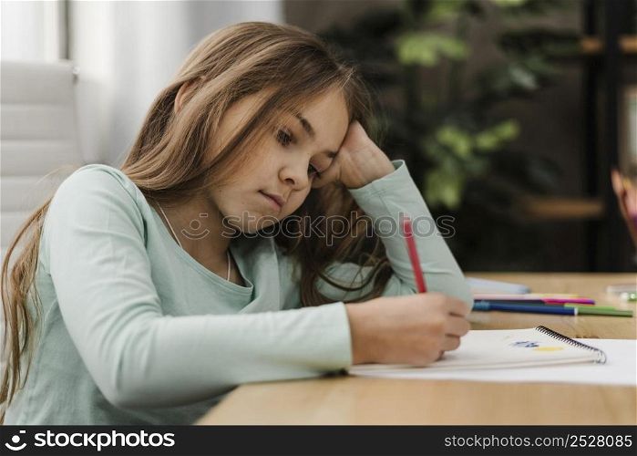 little girl taking notes while being bored home