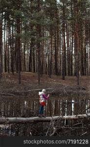 little girl tourist walks on a fallen tree on the lake. wild conditions