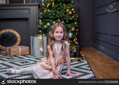 Little girl under the Christmas tree. A girl with gifts under the tree in anticipation of magic, a gift from Santa Claus. Little girl under the Christmas tree. A girl with gifts under the tree in anticipation of magic