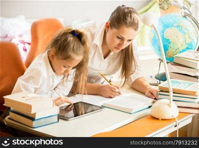 Little girl using digital tablet while mother doing homework instead of her