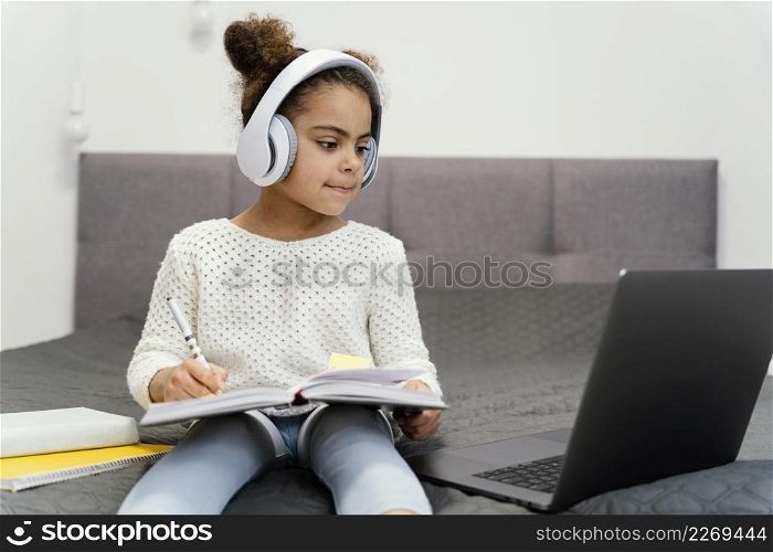 little girl using laptop headphones online school