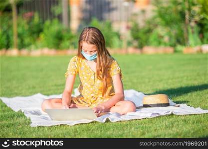 Little girl using laptop to study outdoors in the park. Little girl outdoors in the park with computer