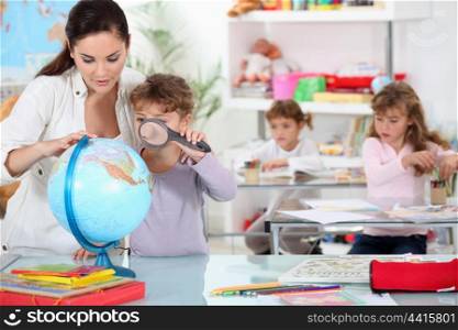 Little girl using magnifying glass on globe