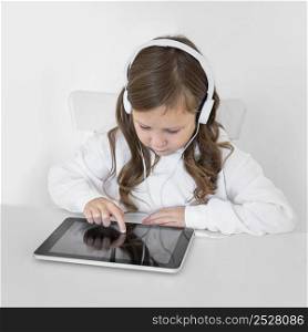 little girl using tablet with headphones