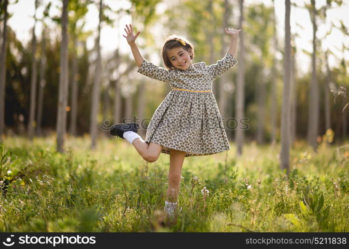 Little girl walking in nature field wearing beautiful dress