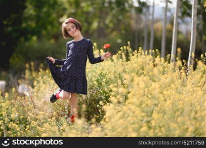 Little girl walking in nature field wearing beautiful dress with flowers in her hand.
