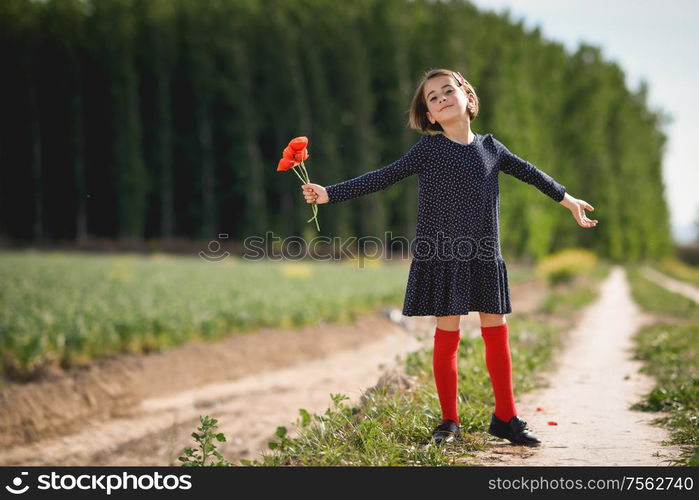 Little girl walking in nature field wearing beautiful dress with flowers in her hand.. Little girl walking in nature field wearing beautiful dress