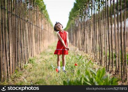 Little girl walking in nature field wearing beautiful red dress