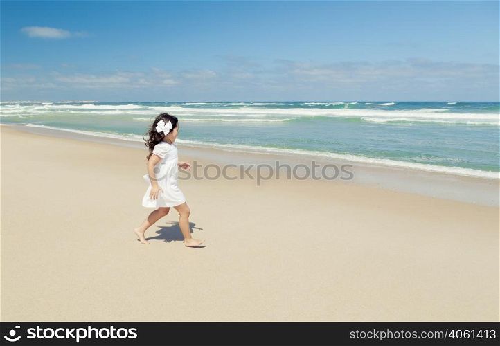 Little girl walking on the beach with a white dress