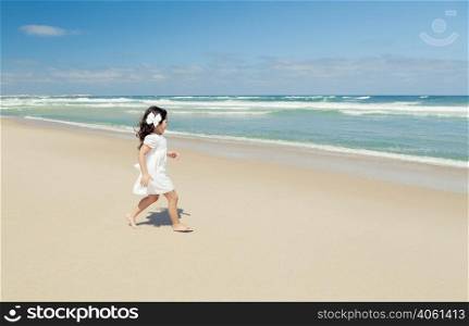 Little girl walking on the beach with a white dress