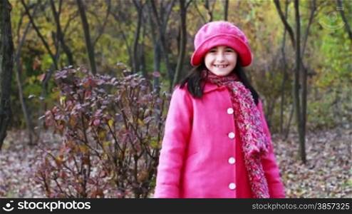 Little girl walking through the woods in autumn season