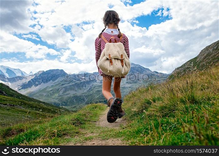 Little girl walks on mountain trail during an excursion. with the backpack.