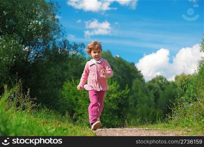 little girl walks on path outdoor in summer