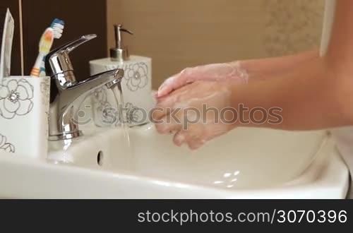 Little girl washes her hands in the bathroom.