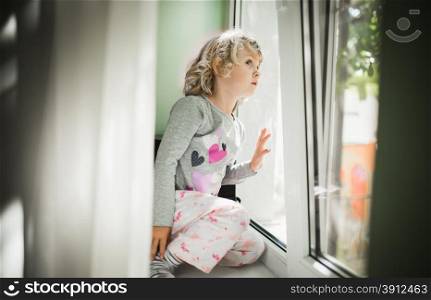 Little girl watching out of a window