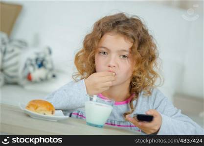 Little girl watching TV as she has her breakfast
