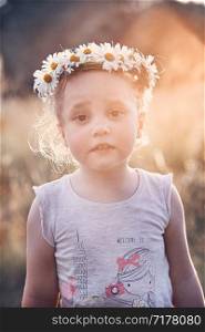 Little girl wearing a coronet of wild flowers on her head. Candid people, real moments, authentic situations