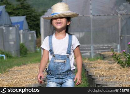 Little girl wearing a hat helps her mother in the garden, a little gardener. Cute girl playing in the vegetable garden.
