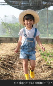 Little girl wearing a hat helps her mother in the garden, a little gardener. Cute girl playing in the vegetable garden.