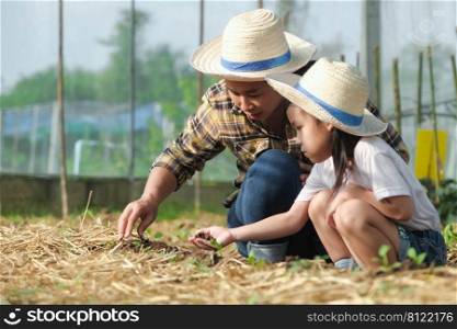Little girl wearing a hat helps her mother in the garden, a little gardener. Cute girl planting vegetables in the garden.
