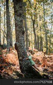 Little girl wearing a wool cap in an autumn forest among ferns