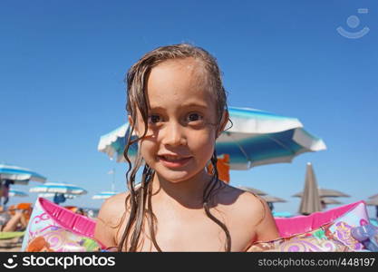 Little girl wearing arm floats on the beach