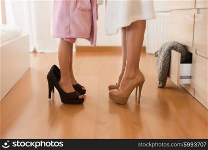 Little girl wearing heels with her mother in bedroom