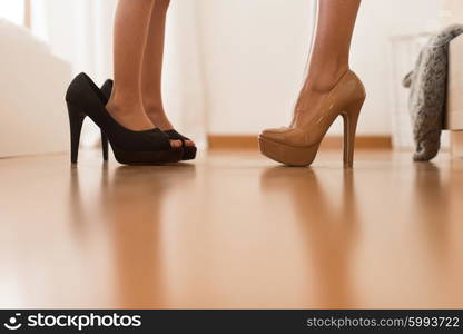 Little girl wearing heels with her mother in bedroom