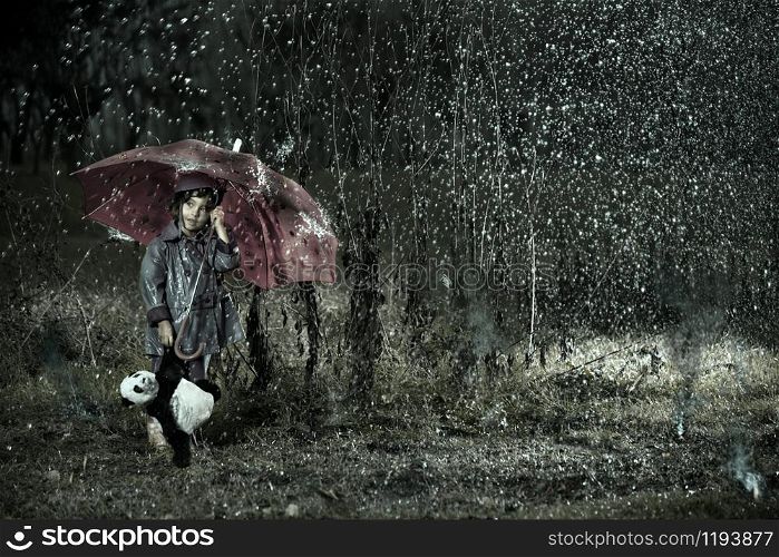 little girl wearing rain coat under a red umbrella with a panda bear toys under a stormy acid rain