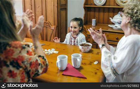 Little girl winning domino her mother and her grandmother. Little girl winning domino